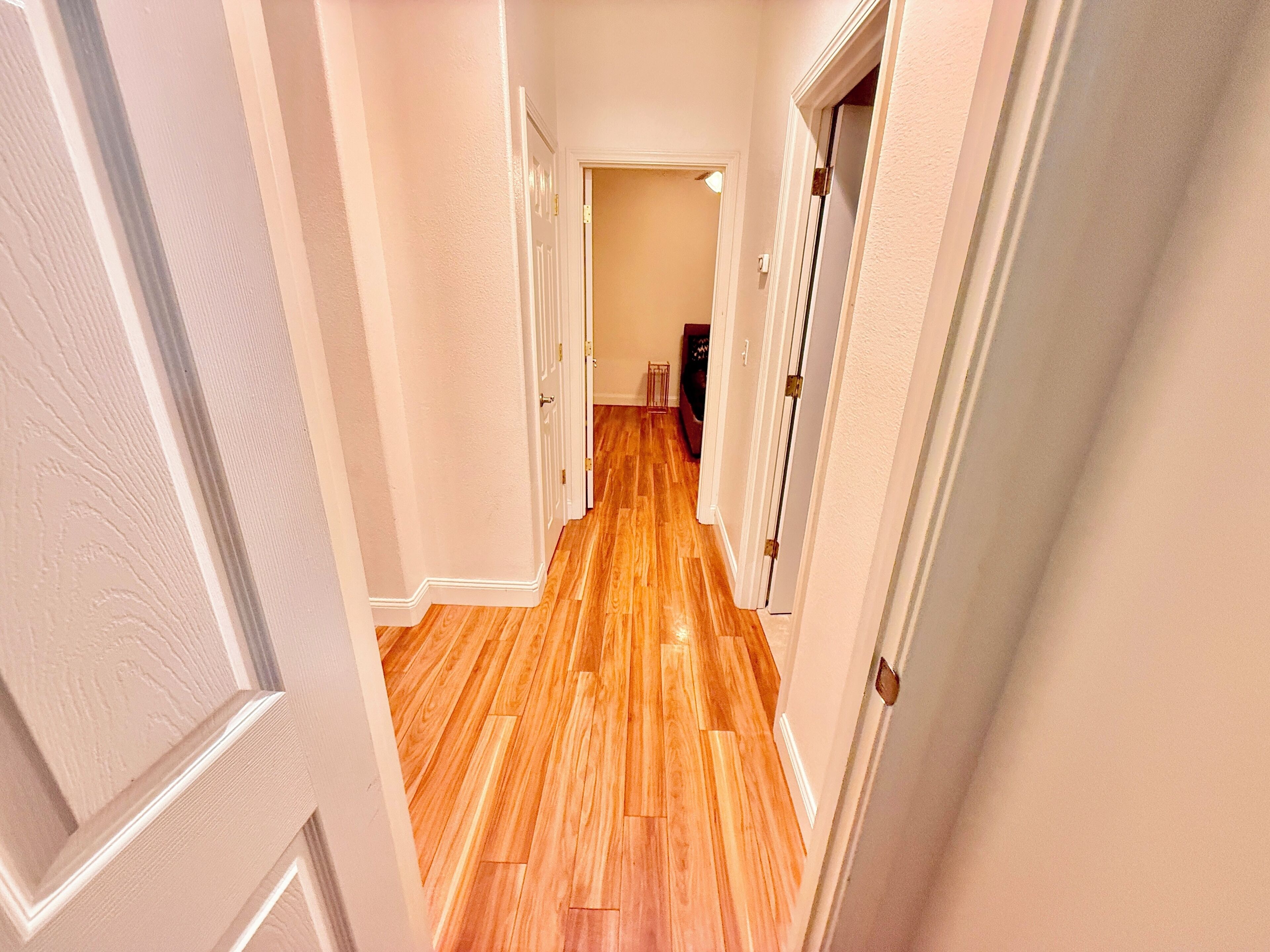 A hallway with wooden flooring and white walls.