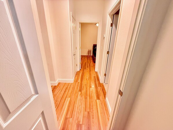 Un couloir avec un plancher en bois et des murs blancs.