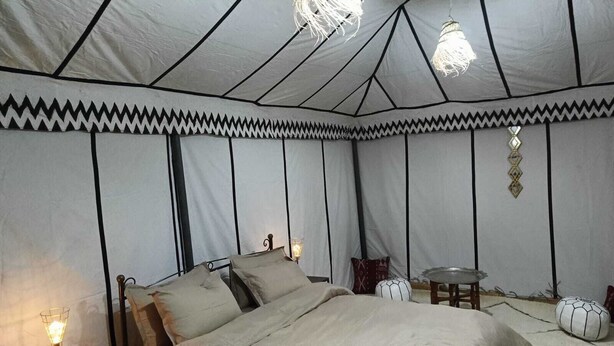 Una habitación con carpa, una cama, una mesita de noche y lámparas colgantes.