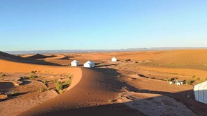 Paisaje desértico con tiendas blancas y cielo despejado.