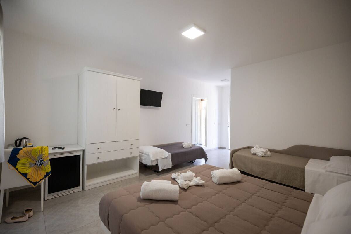 A hotel room with a bed, a desk, a wardrobe, and a television.