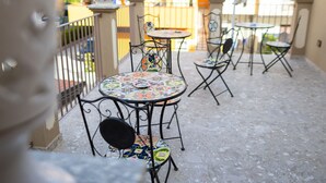 A patio with round tables and chairs, outdoor decor, and a view of the surrounding area. - B&B Allison Tropea (Tropea)