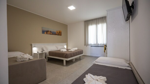 A hotel room with two beds, a sofa, a flat-screen TV mounted on the wall, and a painting on the wall. - B&B Allison Tropea (Tropea)