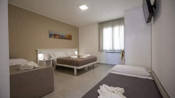 Una camera d'albergo con due letti, un divano, una TV a schermo piatto montata a parete e un quadro appeso al muro.