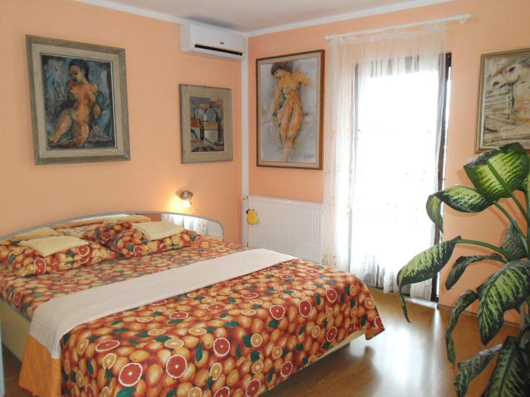 A bedroom with a bed, a radiator, and a window with curtains.