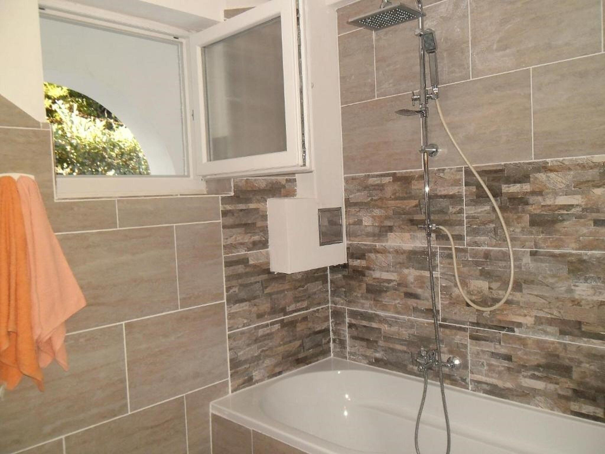 A bathroom with a bathtub, a shower, and a window.