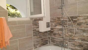 A bathroom with a bathtub, a shower, and a window.