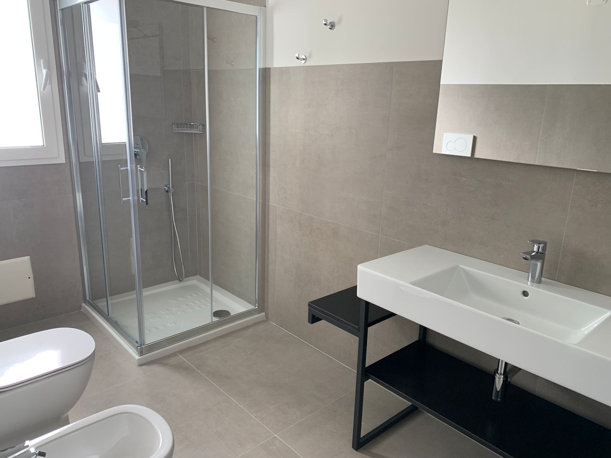 Un baño moderno con ducha de vidrio, lavamanos blanco y retrete.
