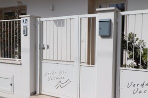 Ein weißes Anwesen mit einem Tor, einem Schild mit der Aufschrift "Verde Blu Vacanze" und einem Briefkasten.