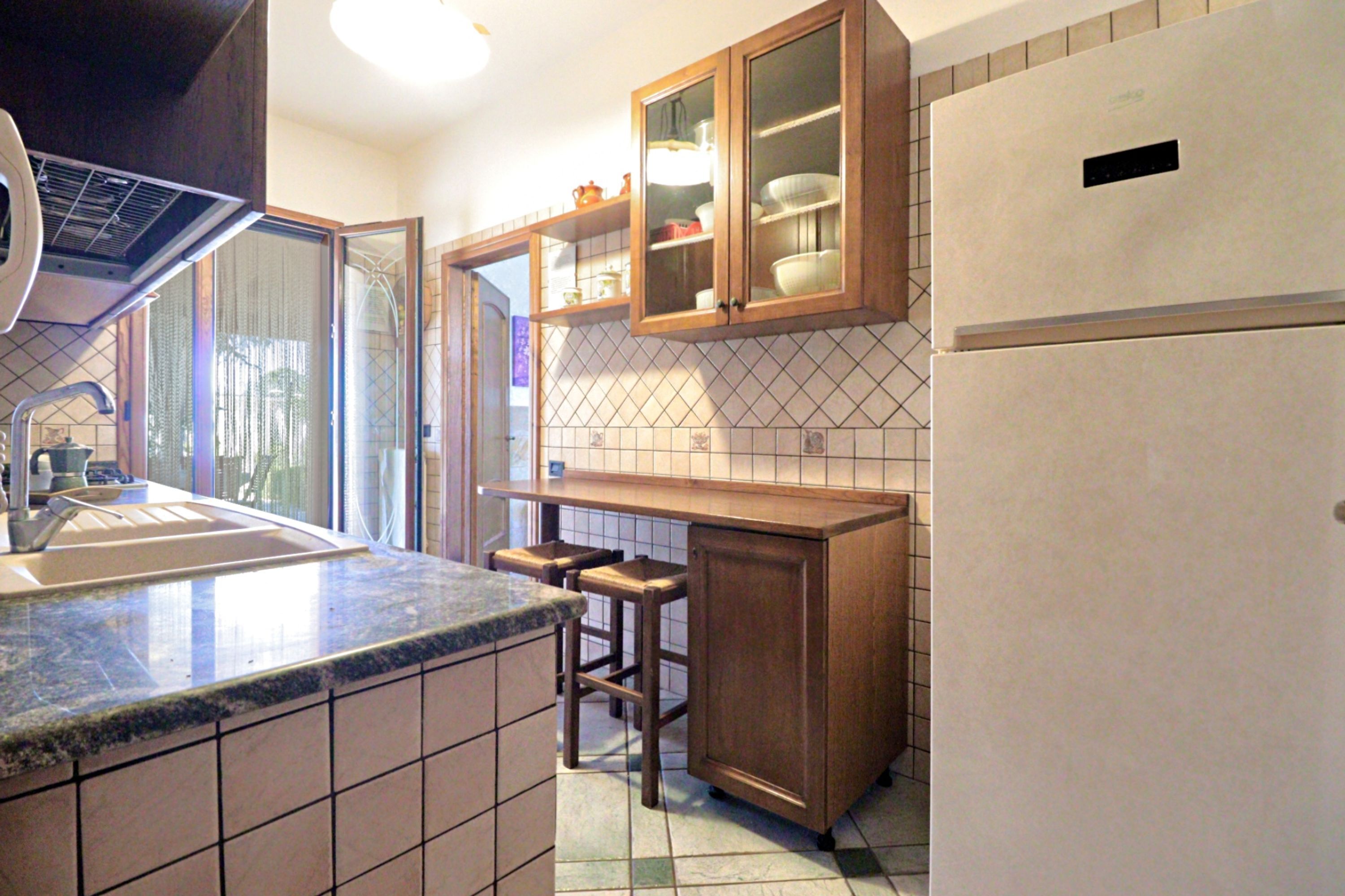 Una cocina con un lavamanos, armarios de madera y un refrigerador.