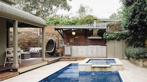 A backyard with a swimming pool, outdoor seating, a barbecue area, and a kitchen with a pergola. - Luxury Retreat | Pool • Fireplace • Parking (Lower Plenty)