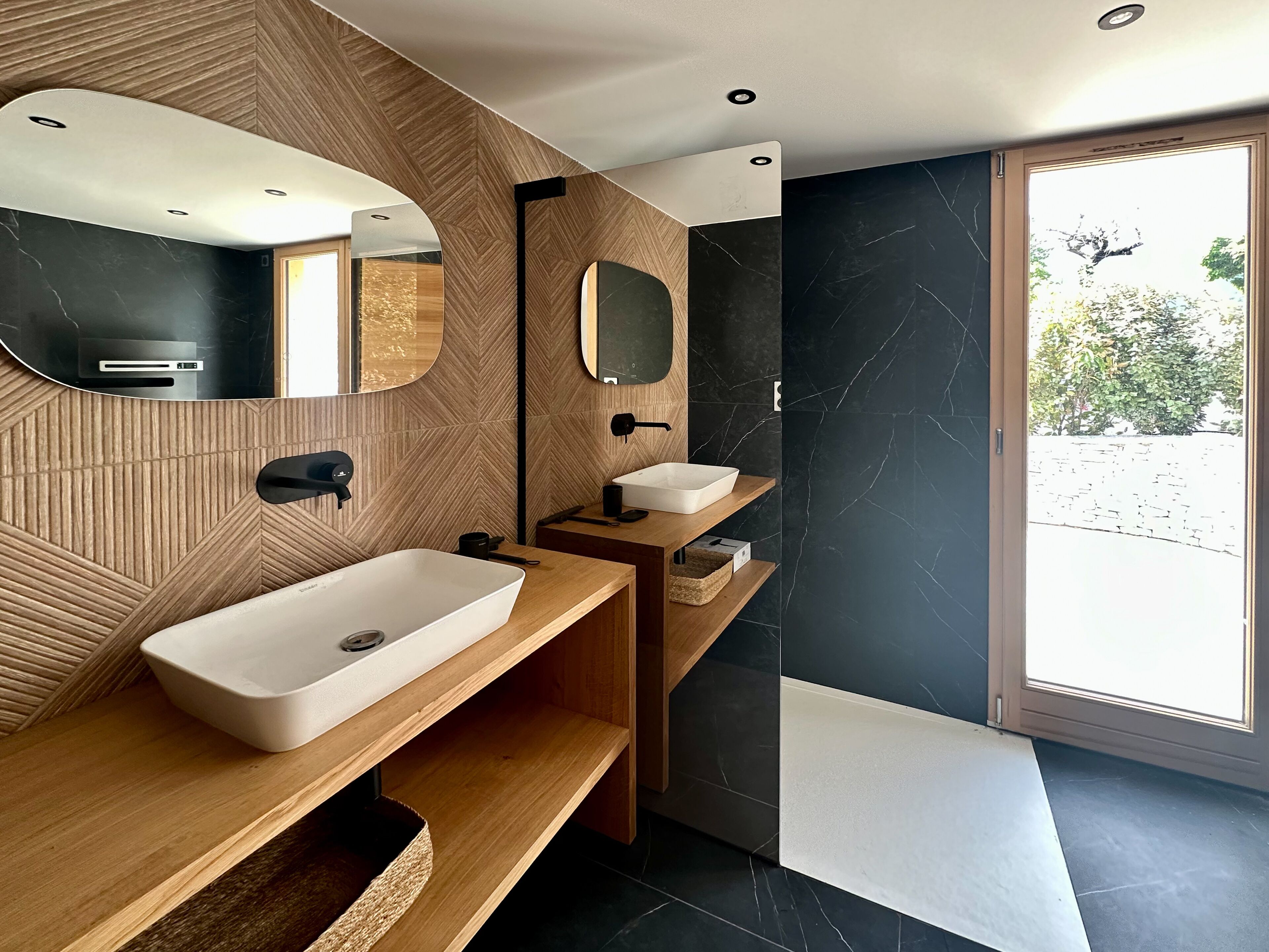 Un bagno moderno con uno specchio grande, un lavandino bianco e un mobile vanitario in legno.