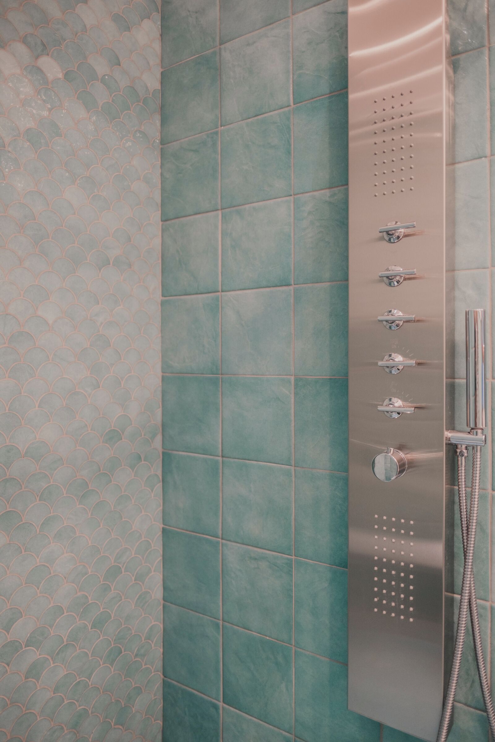 A shower with a control panel and a handheld showerhead.