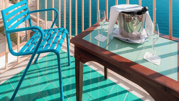 A balcony with a table and chairs overlooking a coastal view. - Villa Nettuno (Positano)