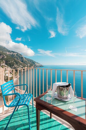 A balcony with a table and chairs overlooking a coastal view. - Villa Nettuno (Positano)