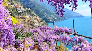 A coastal town with buildings on a hillside, overlooking the sea. - Villa Nettuno (Positano)
