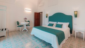 A bedroom with a bed, a bedside table, a chair, and a small table with a plant. - Villa Nettuno (Positano)