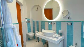 Un bagno moderno con uno specchio rotondo, un lavandino, un bidet e un porta asciugamani.