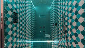 A bathroom with a geometric tile pattern, a shower area, and a towel rack. - Villa Nettuno (Positano)