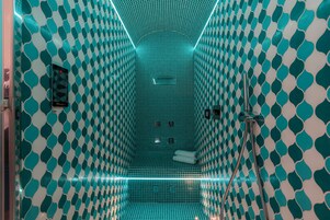 Un baño con un patrón geométrico de azulejos, una zona de ducha y un perchero.