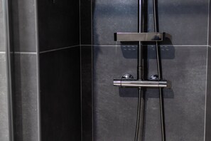 A modern shower enclosure with a chrome faucet and hose.