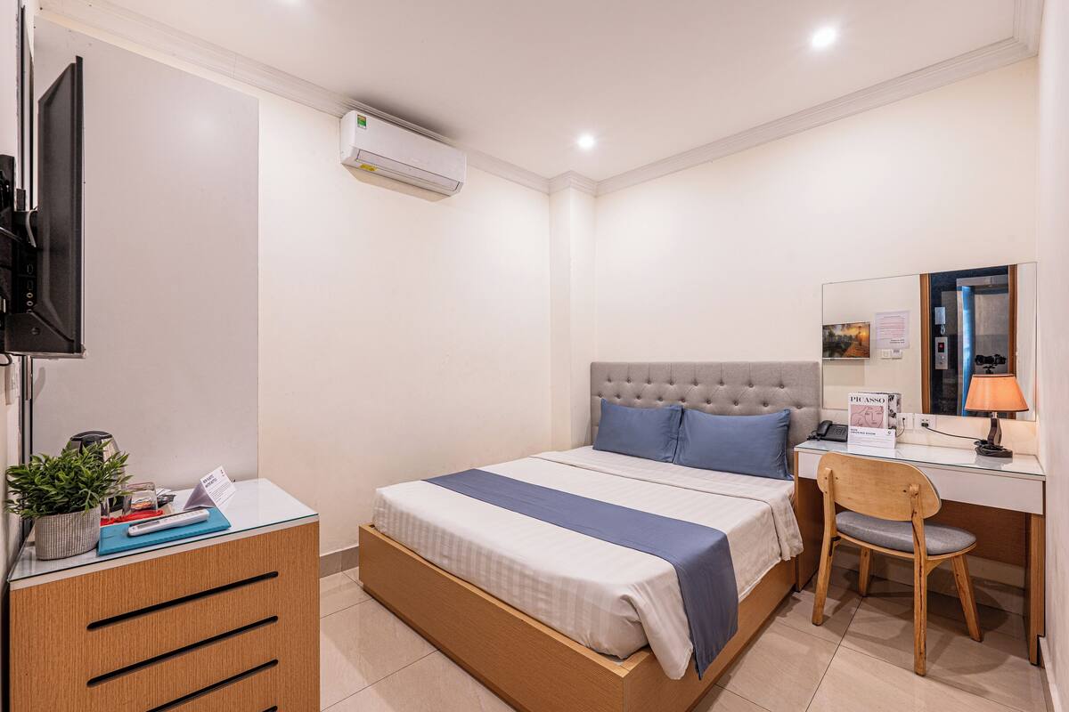 Une chambre d’hôtel équipée d’un lit, d’un bureau, d’une chaise, d’une télévision et d’un appareil de climatisation.