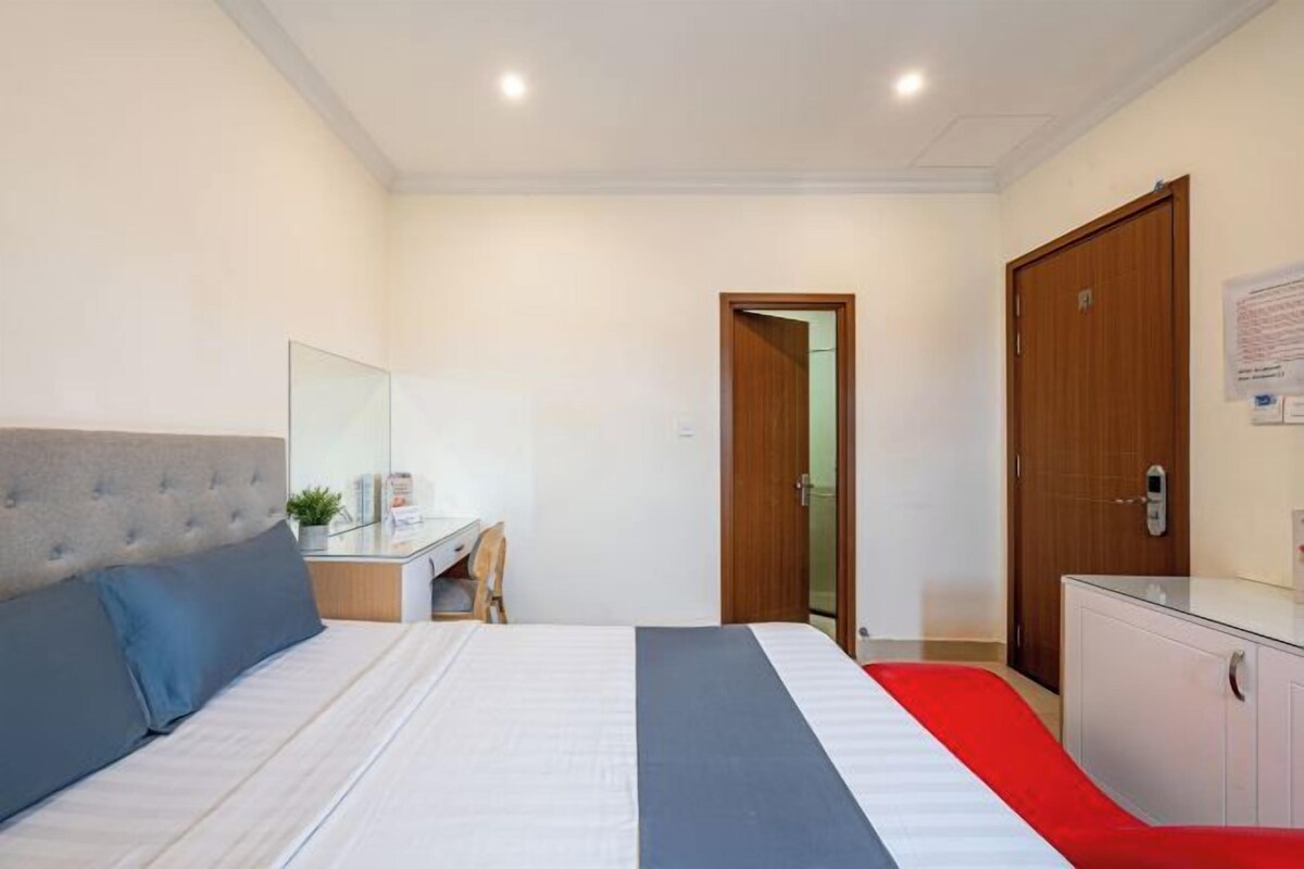 Habitación de hotel con cama, escritorio, armario y espejo.