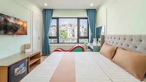 A hotel room with a bed, a desk, a chair, a TV, and a window with a city view. -  Cozrum - Love Hotel Trần Thị Nghỉ (Ho Chi Minh City)