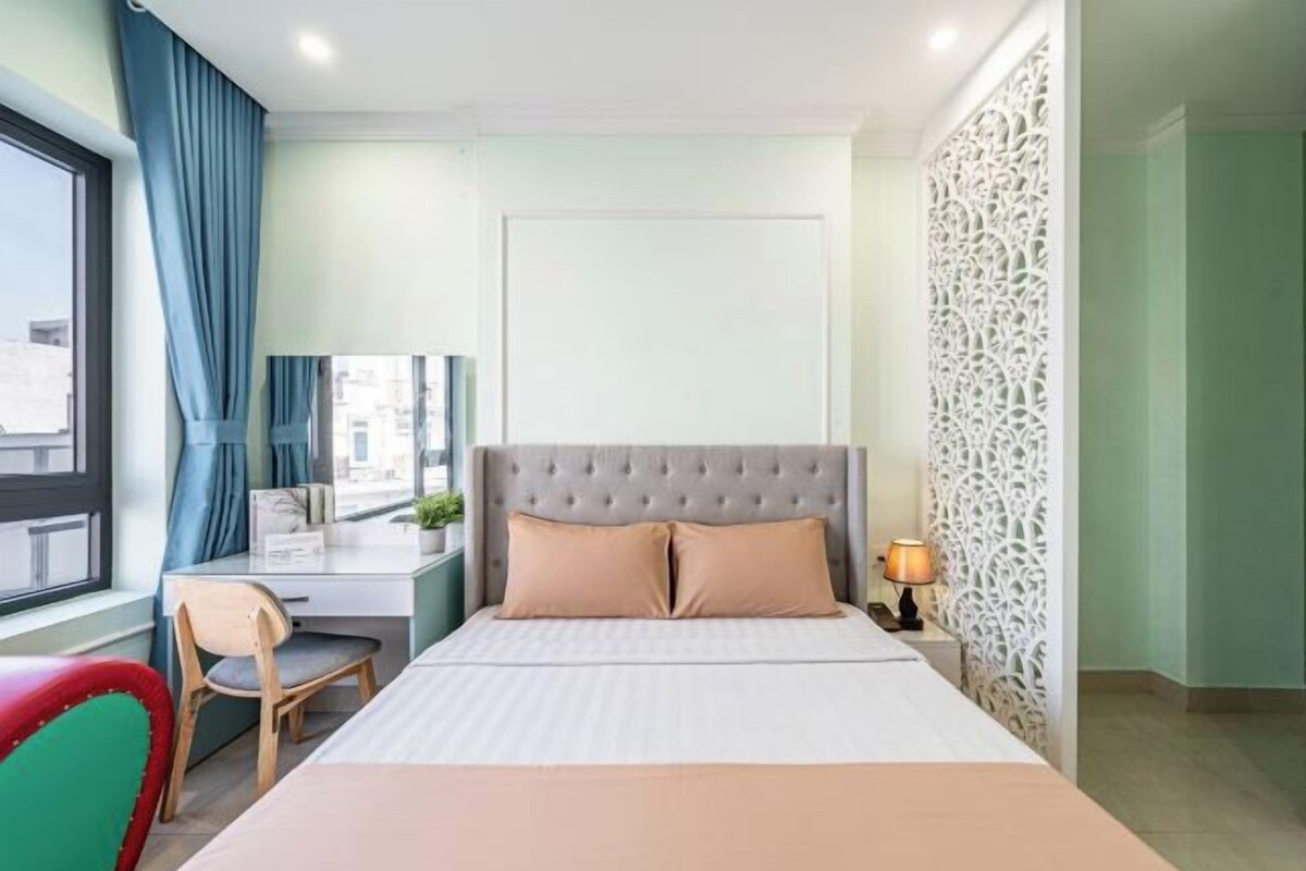 Habitación de hotel con cama, escritorio, silla y ventana con cortinas.