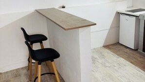 A small kitchenette with a white countertop, two black chairs, and a wooden ceiling. - Comfortable air-conditioned mahogany T2 Lamentin near Galleria shopping center (Le Lamentin)