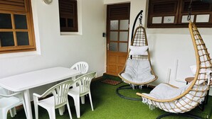 A room with a white table and chairs, a hanging chair, and a door with frosted glass panels. - Comfortable air-conditioned mahogany T2 Lamentin near Galleria shopping center (Le Lamentin)
