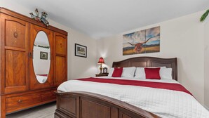Un dormitorio con una cama de madera, un armario grande y un cuadro en la pared.