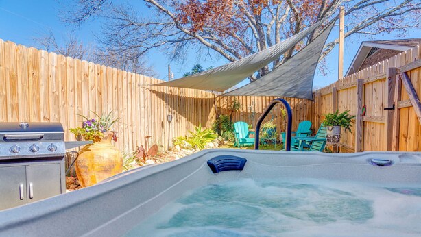 Un jacuzzi con una valla de madera y sillas al fondo.