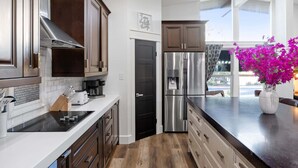 Una cocina moderna con electrodomésticos de acero inoxidable, armarios de madera y encimera negra.