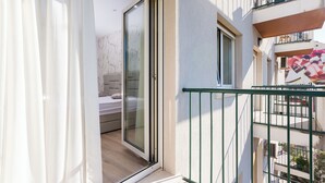 A balcony with a sliding glass door leading to a bedroom with a bed and a sofa. - Shine of Life Luxury Rooms (Split)