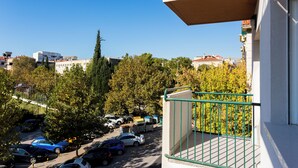 A view from a balcony overlooking a parking lot with several cars, trees, and buildings in the background. - Shine of Life Luxury Rooms (Split)