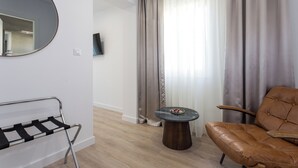 A modern living room with a leather sofa, a round table, a metal bench, and a large mirror on the wall. - Shine of Life Luxury Rooms (Split)