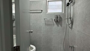 Un baño moderno con inodoro, ducha y ventana.