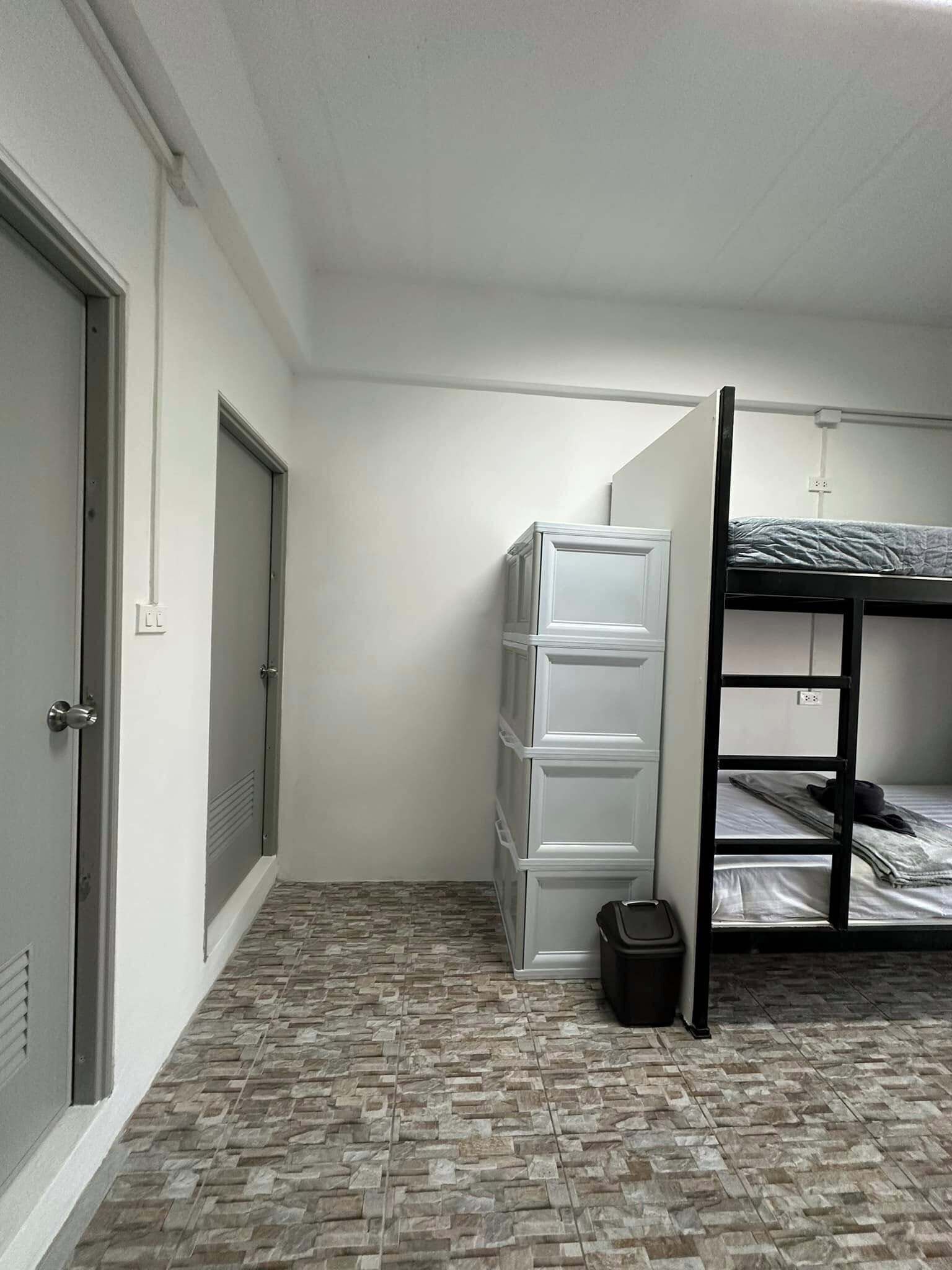 A room with a bunk bed, a white wardrobe, and a tiled floor.