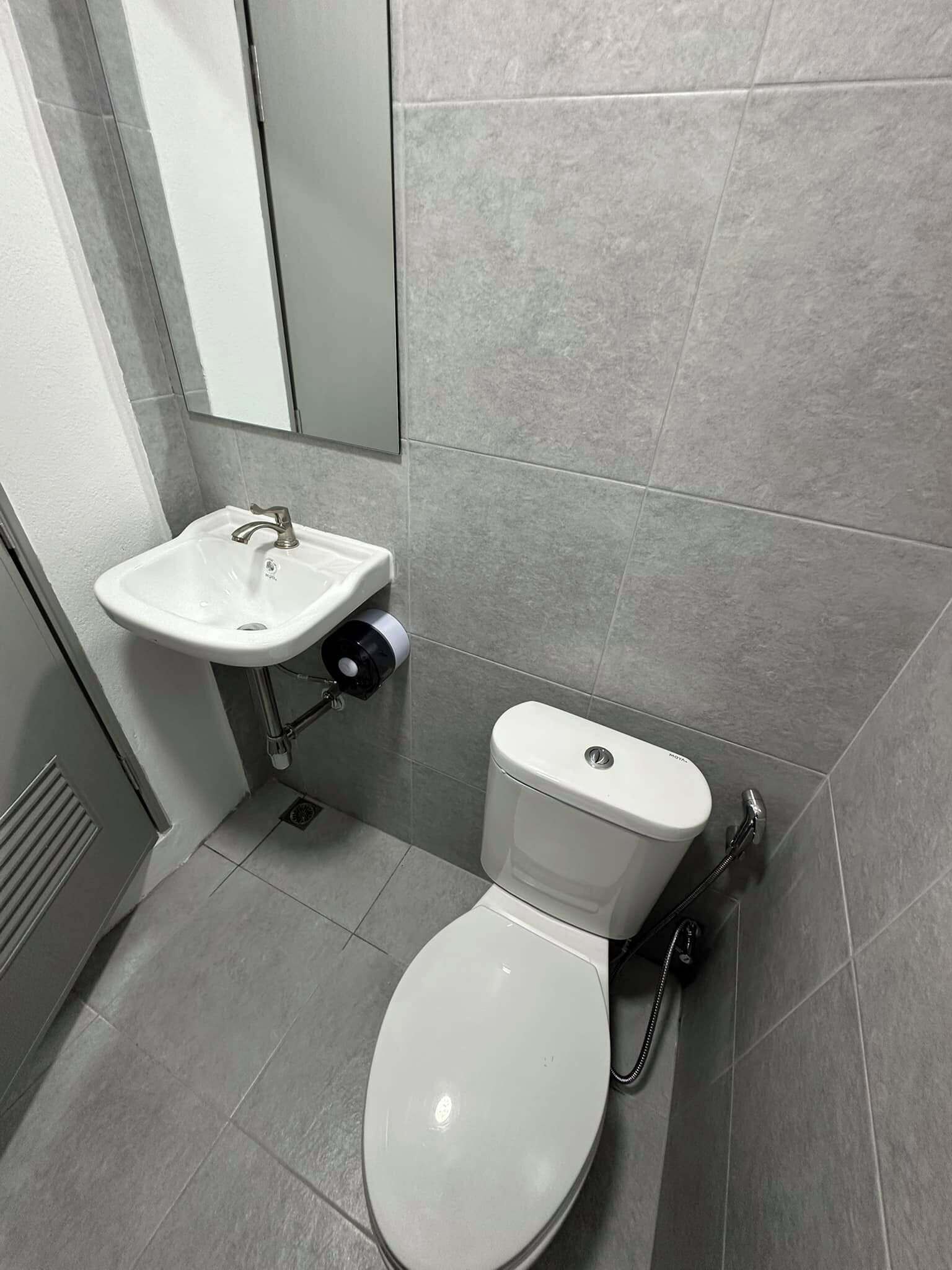 A bathroom with a white sink, toilet, and a mirror.