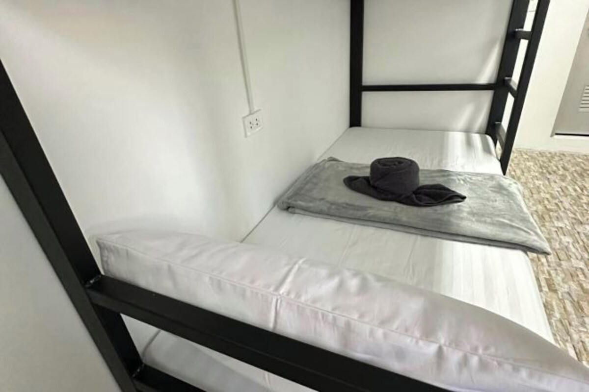 A single bed with a black metal frame and white bedding.