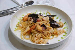 En tallrik pasta med skaldjur, garnerad med färska örter.