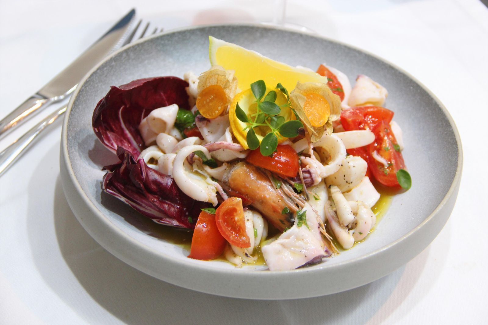 A plate of seafood salad with lemon and herbs.