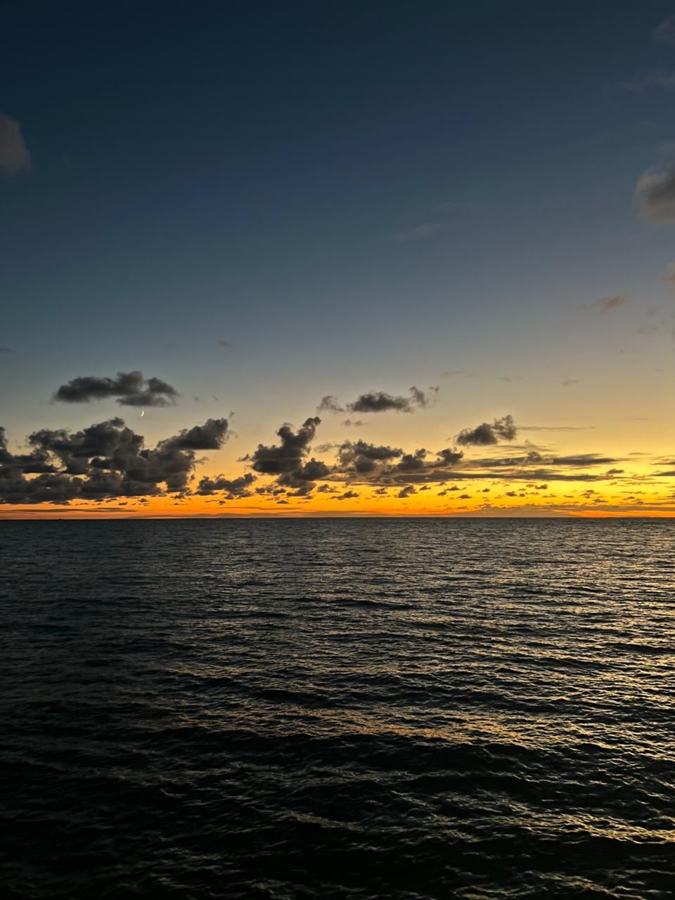 A sunset over a body of water with clouds in the sky.