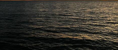 A sunset over a body of water with clouds in the sky.