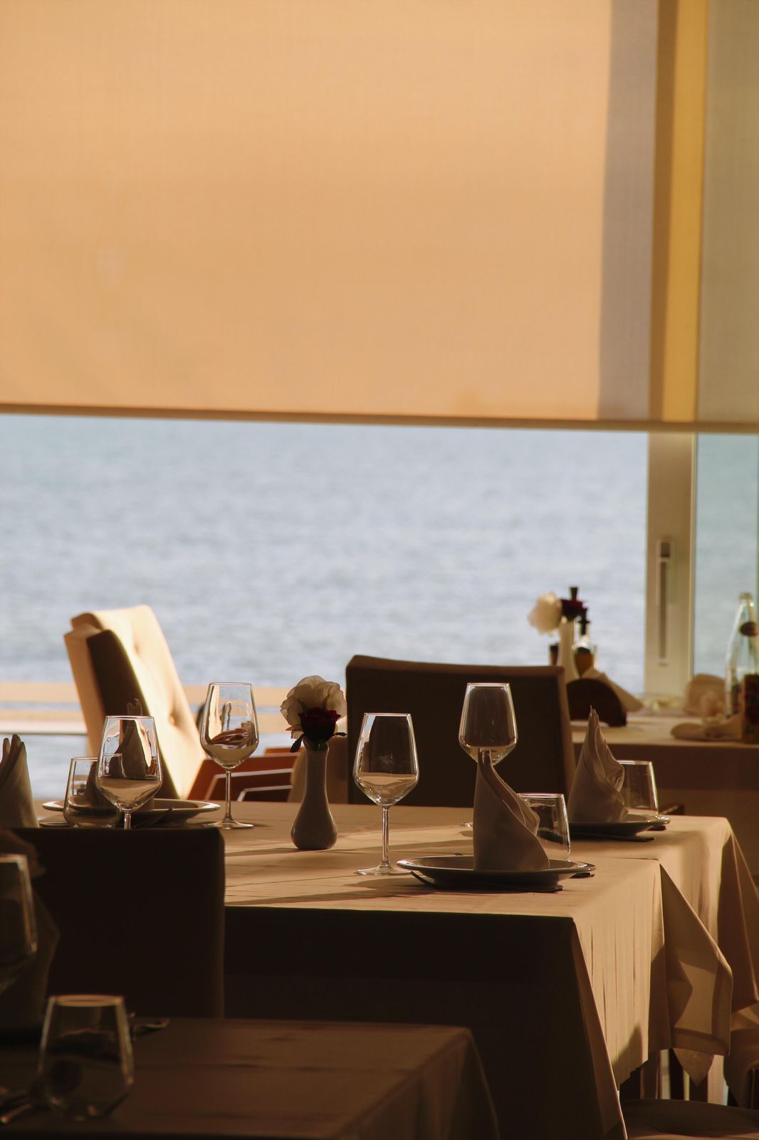 A dining table set for two with a view of the sea.