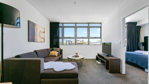 A modern hotel room with a sofa, a small round table, a TV, and a bed. - free parking lovely 2 bds  in heart of chatswood (Chatswood)