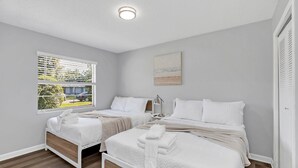 A bedroom with two beds, a window with blinds, a painting on the wall, and a ceiling light. - Backyard BBQ home - Blue Spring to Daytona (Orange City)