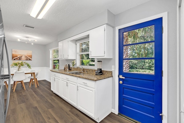 Kitchen with granite countertops and a vibrant blue door overlooking greenery.