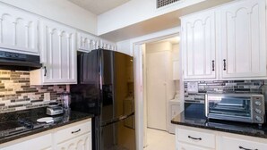 A kitchen with white cabinetry, a black refrigerator, a toaster oven, and a blender on the counter. - Spacious 4BR with Private Pool, Near Six Flags (San Antonio)